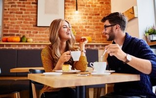 Couple of young people drinking coffee and eating cake in a stylish modern cafeteria