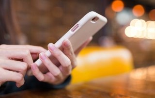 Woman texting on mobile phone in coffee shop