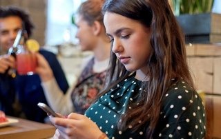 woman with smartphone and friends at restaurant