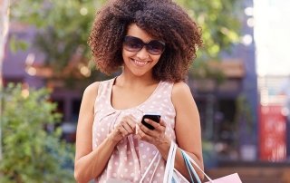 Smiling woman using her phone outdoors while shopping