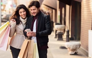 Shopping together. Millennial couple using smartphone outdoors